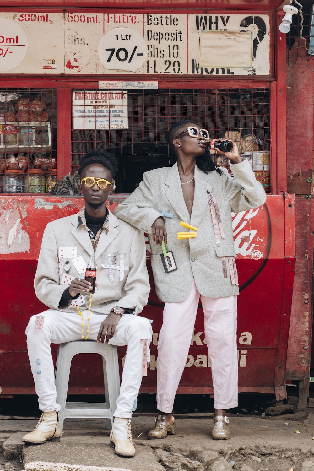 2 personnes kenyannes devant un kiosque de boisson en train de boire un Coca-Cola